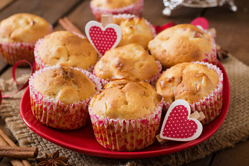 Tasty muffins with apple and cinnamon on a wooden background