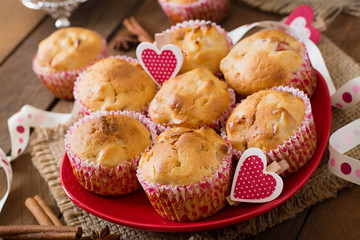 Tasty muffins with apple and cinnamon on a wooden background