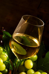 White wine and green grapes in a wicker basket in a wine cellar,