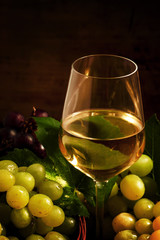 White wine and green grapes in a wicker basket in a wine cellar,