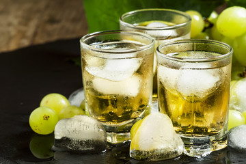 Cold grape juice with ice on dark background, selective focus