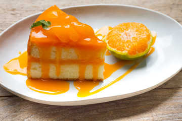 orange cake with orange topping in wooden dish
