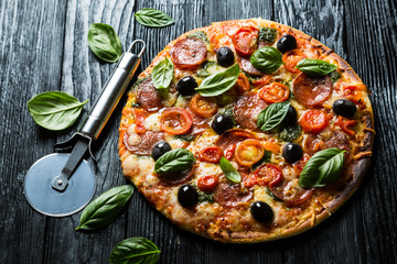 Pizza with salami, olives and basil