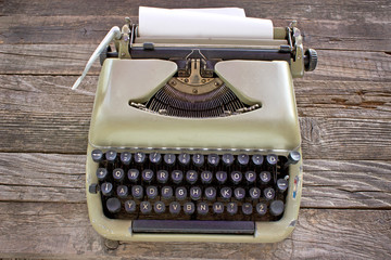 Old typewriter with blank paper on wooden background