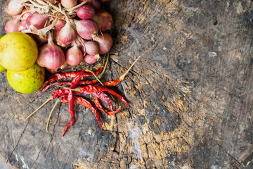 Red onion green lemon dried hot chili pepper on wooden chopping block