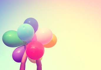 Girl hand holding multi colored balloons done with a retro vintage instagram filter effect, concept of happy birth day in summer and wedding honeymoon party (Vintage color tone)