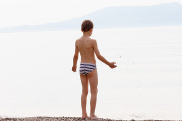 boy throwing rocks into the sea
