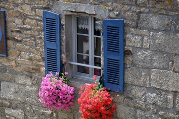 Fenster mit blauen Fensterläden und Geranien