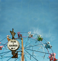 aged and worn vintage photo of ferris wheel with fun and games sign