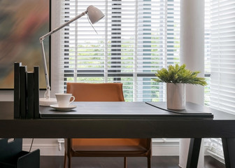 wooden table with lamp and books in modern working room interior