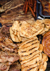 Delicious grilled meat with vegetable on a barbecue. Closeup of fried meat and sausages on a grill.