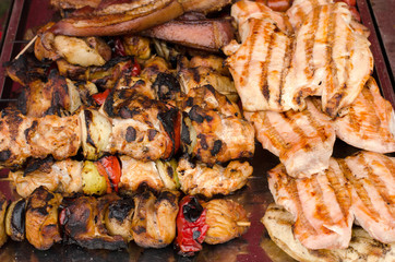 Delicious grilled meat with vegetable on a barbecue. Closeup of fried meat and sausages on a grill.