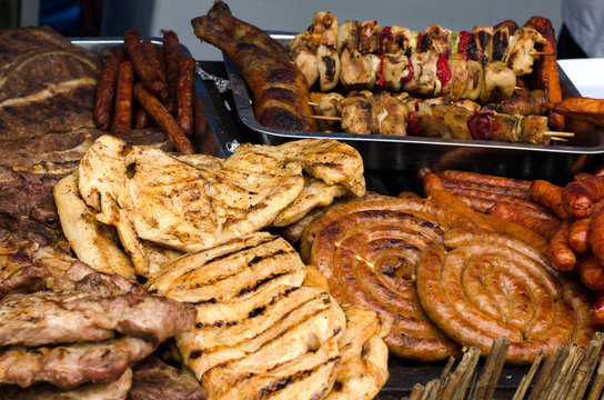 Delicious grilled meat with vegetable on a barbecue. Closeup of fried meat and sausages on a grill.