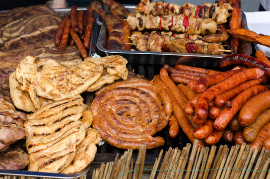 Delicious grilled meat with vegetable on a barbecue. Closeup of fried meat and sausages on a grill.