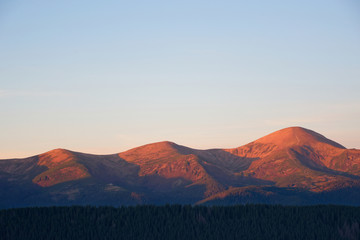 Fototapeta na wymiar View of rosy mountain peaks of Chornogora range in Carpathians at the sunrise with Horverla the highest mountain of Ukraine