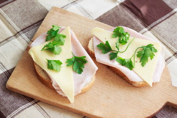 Slice of bread with ham, cheese, herbs and red tomato