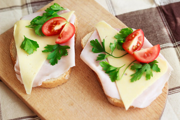 Slice of bread with ham, cheese, herbs and red tomato