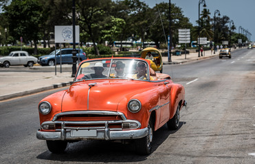 Kuba el Malecon in Havanna auf der Strasse fahrender amerikanischer orangener Cabriolet Oldtimer