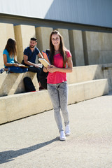 portrait of an attractive cheerful young student woman outdoor in front of high school campus