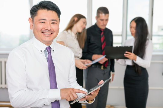 Executive asian boss using tablet pc with his business team