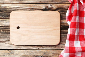Empty wooden table with cutting board and napkin on brown backgr