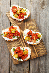 Tasty fresh bruschetta with tomatoes on cutting board on grey wo