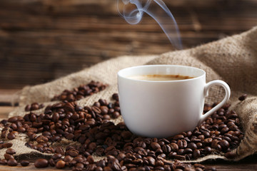 Cup of coffee with coffee beans on a brown wooden background