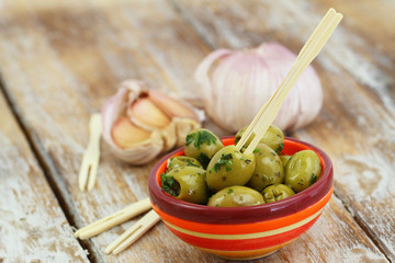 Green olives with garlic on rustic wooden surface with copy space
