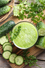 Glass of fresh cucumber juice on grey wooden table