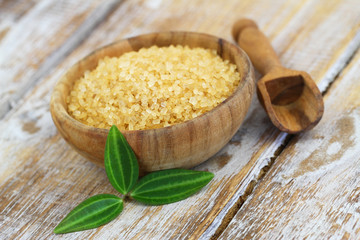 Brown sugar in wooden bowl on rustic wooden surface
