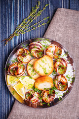 Fried snails with garlic butter and herbs on dark background