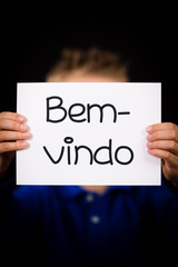 Child holding sign with Portuguese word Bem-vindo - Welcome