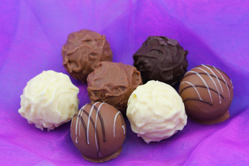 Assorted chocolates, pralines and truffles on purple background
