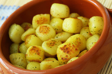 Roasted baby potatoes in traditional clay bowl, closeup
