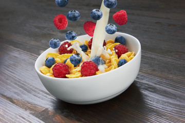 Falling corn flakes with fresh berries and pouring milk