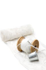 Fototapeta na wymiar roll of white lace, a wooden spool of white cotton thread for