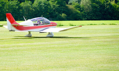 Fototapeta na wymiar red sports plane on a meadow