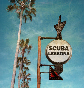 aged and worn vintage photo of scuba lessons sign with palm trees
