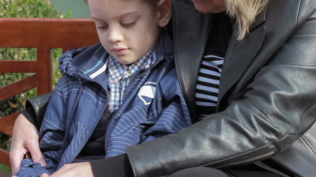 Grandmother and grandson playing together on e-reader sitting at bench 