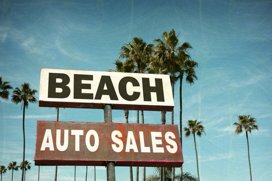 aged and worn vintage photo of auto sales sign on beach