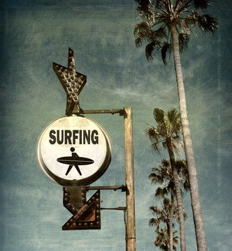 aged and worn vintage photo of surfing sign on beach