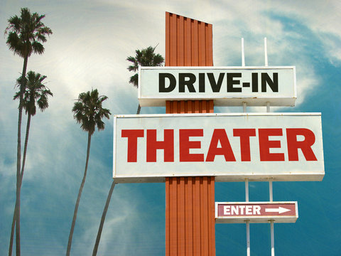 aged and worn vintage photo of drive in theater sign with palm trees