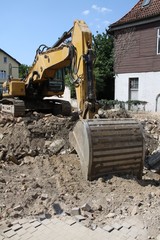 Obraz premium Gelber Schaufelbagger bei Abbrucharbeiten