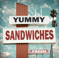 aged and worn vintage photo of yummy sandwiches sign