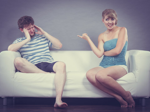 Man and woman having argument sitting on sofa at home