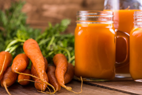Carrot juice in mason jar on wooden background