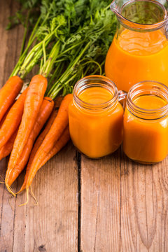 Carrot juice in mason jar on wooden background