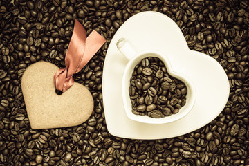 Heart shaped cup and cookie on coffee beans background
