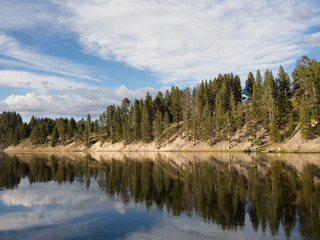 Scenic view of the mirror like water surface of the Yellowstone River and partly cloudy blue sky, Yellowstone National Park.