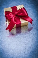 Wrapped golden present with red ribbon bow top view